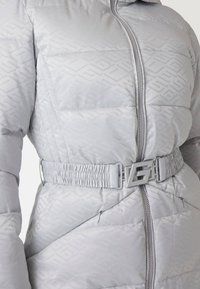 Lysegrå dunjakke med en glat overflade, der har en mønstret tekstur, elastisk talje med logo-spænde og lynlåslommer.