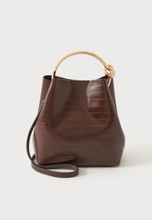 Sac à main marron foncé à texture crocodile avec poignée ronde en métal doré et longue bandoulière assortie sur fond blanc.