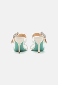 Sandali bianchi con tacco alto caratterizzati da una suola verde menta in contrasto, adornati con dettagli in perle e una fibbia decorativa sul tallone.