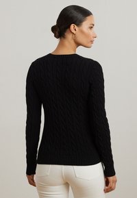 Svart kabelstrikket genser med lange ermer og rund hals, med ribbestrikket kant på ermene og nederste del. Glatt tekstur og tettsittende design.