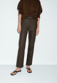 Brown knitted sweater, high-waisted dark brown straight-leg pants, and black flat sandals. Minimalist design, soft texture, and simple accents.