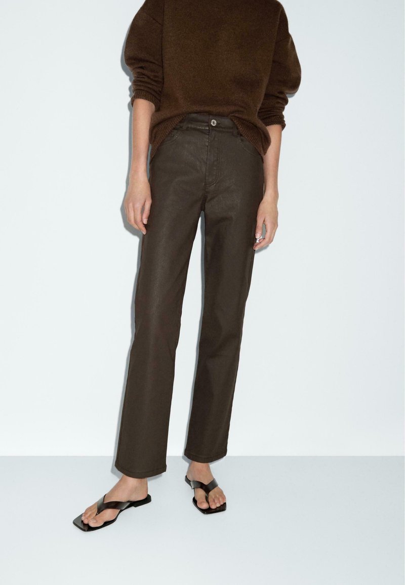 Brown knitted sweater, high-waisted dark brown straight-leg pants, and black flat sandals. Minimalist design, soft texture, and simple accents.