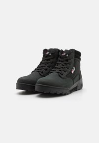 Bottes mi-hautes noires avec un dessus en daim et en maille, dotées de lacets noirs, d'un col rembourré et d'un accent de logo. Semelle en caoutchouc robuste pour une meilleure traction.
