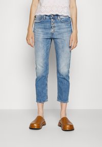 Ljust blå, högmidjade jeans med knapplåsfunktion, avkortad längd och bleka detaljer. Matchas med bruna slip-on klackar.