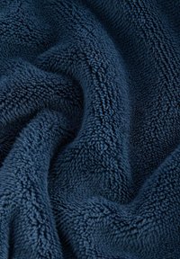 Marinblå fleece med en mjuk, plyschliknande textur. Den har en tjock, fluffig yta och små oregelbundenheter i fibrerna.
