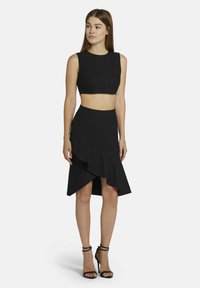 Zwart twee-delig outfit met een mouwloze crop top en een knie-lange rok met een gerimpelde zoom. Gestructureerde stof met subtiele glans.