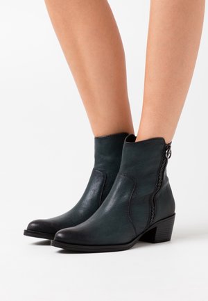 Botines de cuero verde oscuro con tacón grueso, cremalleras laterales y acabado liso. Presentan punteras negras en contraste y costuras detalladas.