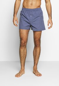 Calções de banho quadriculados azuis com cintura elástica e botão frontal. Tecido leve, comprimento acima do joelho e sem forro.