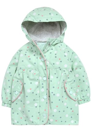 Veste de pluie vert clair avec des pois blancs, roses et gris. Elle dispose d'une capuche, d'une fermeture à pression et de deux poches avant aux bords arrondis.