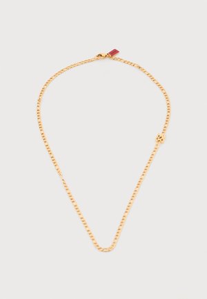 Guldhalskæde med lille firkløvervedhæng og karabinlås på lysegrå baggrund.