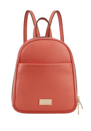 Sac à dos en cuir corail, de forme arrondie, avec une poche zippée à l'avant et un label en métal doré. Dispose de bretelles réglables et d'une texture lisse.