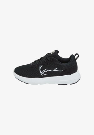 Zapatilla deportiva negra ligera con suela blanca, parte superior de malla, cordones y logo blanco característico en el lateral, diseñada para uso casual.