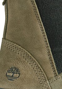 Braune Leder-Stiefelette mit strukturiertem Finish, Textil-Seitenteil, kontrastierendem Nähen und einem runden Logodetail.