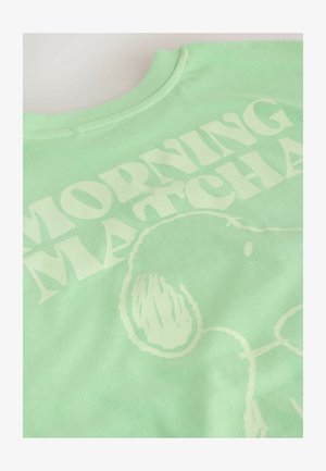 Šviesiai žalias medvilninis marškinėlis su dideliais, ryškiais baltais žodžiais "MORNING MATCHA" ir paprastu grafiniu dizainu. Minkšta tekstūra.