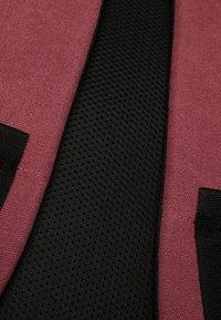 Un tejido texturizado rosa adyacente a un material de malla negra suave, con acentos en negro. El diseño presenta una combinación de colores y materiales.