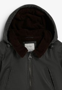 Chaqueta negra con cremallera frontal, cuello de pana marrón y capucha. El interior tiene un forro suave y oscuro. Se ven dos bolsillos laterales.
