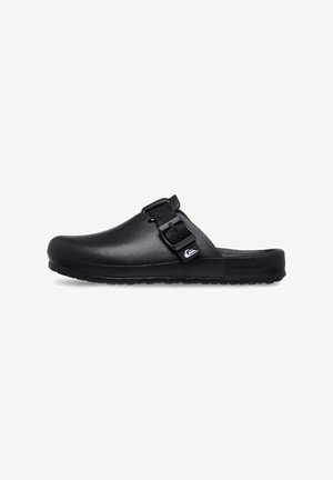 Black clog with a sleek design, made of synthetic material. Features an adjustable strap and textured sole for grip. Logo detail on the side.
