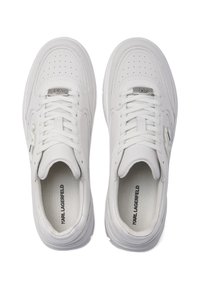 Balti ādas sporta apavi ar caurumošanas elementiem, plakaniem šņorēšanas auklām, mīkstu apkaklīti un zīmolētām iekšējām zolēm. Apaļš purngals un gumijas zole.