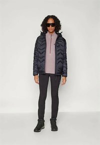 Black puffer jacket with chevron pattern, worn over a light purple fleece top. Black leggings and black hiking boots complete the look.