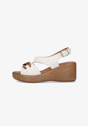 Sandalo zeppa in pelle bianca con suola platform marrone, punta aperta, fibbia decorativa in legno e cinturino regolabile alla caviglia con fibbia dorata.