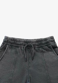 Donkergrijze sweatpants met een elastische tailleband, koordsluiting en zijzakken. Zachte textuur met een gladde afwerking.