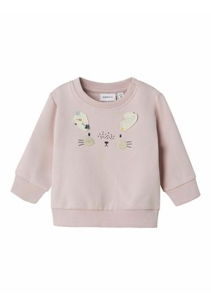 Felpa rosa con una texture morbida, caratterizzata da un design con faccia di coniglio, orecchie pelose e dettagli ricamati. Polsini e orlo a coste.