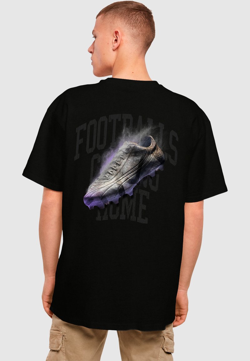 Black t-shirt featuring a graphic of a football boot with grey accents and purple smoke effects, with the text "FOOTBALL'S COMING HOME" in faded lettering.