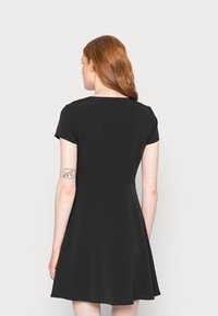 Vestido preto de mangas curtas com um corpete justo e saia godê. Tecido suave, decote redondo e detalhe de fecho na parte de trás.