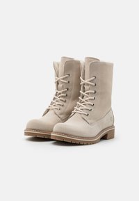 Botines de ante beige con puntera redonda, cierre de cordones, ojales metálicos y suelas de goma con un dibujo texturizado para mayor agarre.
