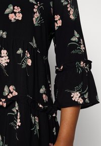 Black floral dress featuring pink flowers and green leaves, with ruffled sleeves and a tiered design for added texture and detail.