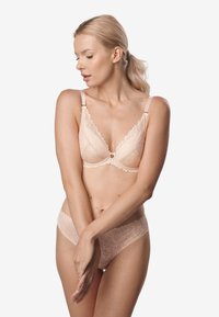 Biustonosz z koronkowym wykończeniem i dopasowane majtki w miękkim odcieniu nude. Ozdobiony kwiatowymi wzorami i regulowanymi ramiączkami, z subtelnymi, błyszczącymi akcentami ze stali nierdzewnej.