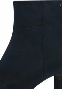 Černá umělá kožená kotníková bota s hladkým povrchem, kulatou špičkou, minimálním šitím a elegantním siluetou. Obsahuje skromný podpatek.