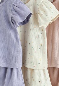 Trois hauts en maille à manches courtes avec des shorts assortis en lavande, crème avec de petites fleurs multicolores et rose poussiéreux.