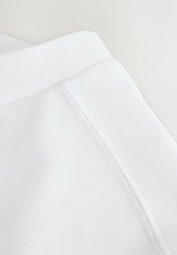 Witte katoen sweatshirtstof met een gladde textuur, voorzien van een geribde manchet en een zijnaadsteekdetail.
