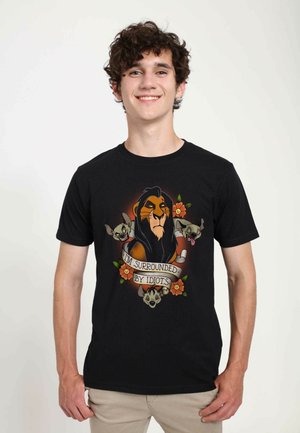 Black cotton t-shirt featuring a graphic design of a lion and animal characters with the text "I'M SURROUNDED BY IDIOTS" and floral accents.