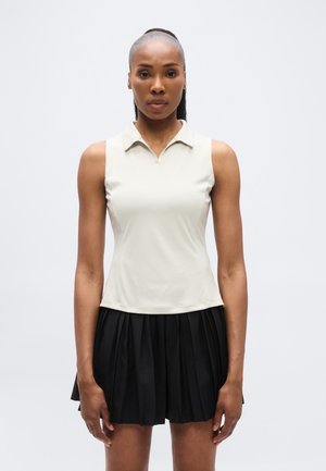 Világos bézs színű ujjatlan felső hajtókás gallérral, fekete pliszírozott szoknyával párosítva, sima textúrával és tiszta dizájnnal.