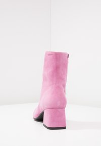 Rosa mockaskinnsankle boots med en fyrkantig klack och dragkedja bak. Slät textur, minimalistisk design.
