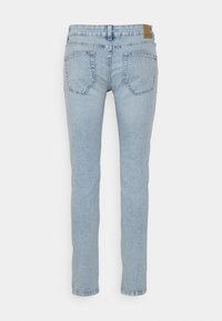 Jeans de lavagem azul clara com um corte slim, apresentando bolsos traseiros, um design de perna reta e uma textura ligeiramente desbotada.
