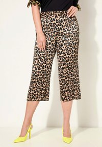 Kalhoty s leopardím potiskem do půli lýtek, s elastickým pasem, hladkým povrchem, doplněné jasně žlutými lodičkami na vysokém podpatku.