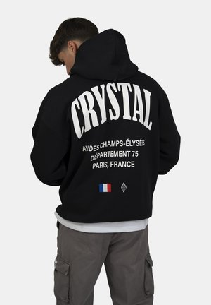 Felpa nera con grande scritta bianca "CRYSTAL" e testo aggiuntivo, con un piccolo dettaglio della bandiera francese sul retro.