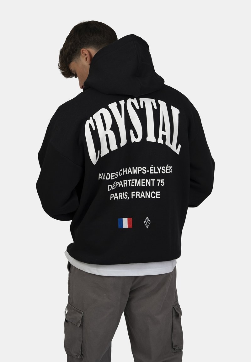 Felpa nera con grande scritta bianca "CRYSTAL" e testo aggiuntivo, con un piccolo dettaglio della bandiera francese sul retro.