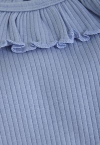 Jasnoniebieska rypsowa tkanina z falbanowym dekoltem, prezentująca delikatną strukturę dzianiny oraz równomierne szycie wokół kołnierza.