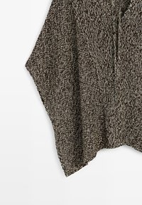 Poncho lavorato a maglia marrone e crema mélange con scollo a V e lati aperti drappeggiati su sfondo bianco.