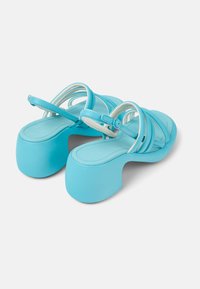 Sandales plateforme bleues en matériau lisse avec des fines lanières et un talon rond, dotées d'une semelle intérieure rembourrée et d'une boucle réglable.