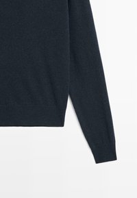 Ciemnoniebieski sweter o gładkiej dzianinie, z prążkowanymi mankietami i dołem oraz klasycznym dekoltem typu crew neck, charakteryzujący się luźnym krojem.