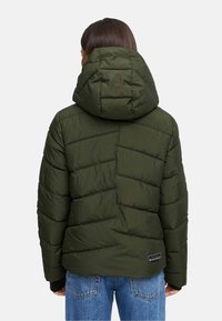Puffjacka i mörk olivgrön, med huva och diagonalt quiltrat mönster. Har en logopatch på baksidan nära botten.