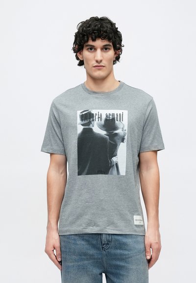 Γκρι βαμβακερό T-shirt με στρογγυλή λαιμόκοψη, με ασπρόμαυρο τυπωμένο γραφικό δύο μορφών. Περιλαμβάνει μια μικρή ετικέτα στο τελείωμα.