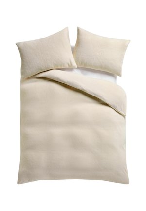 Beiges Bett mit zwei passenden Kissen und einer gefalteten beigen Decke auf einer weißen Matratzenoberfläche.