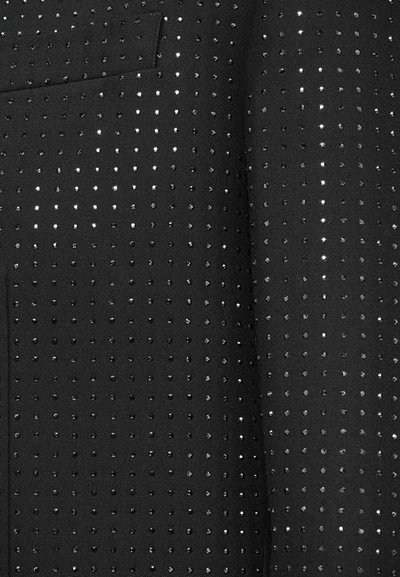 Tessuto nero con un motivo a pois e accenti argentati lucidi. La texture è liscia, con fori distribuiti uniformemente su tutta la superficie.