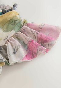 Le tissu en maille multicolore présente un bord froncé. Le design comprend des nuances de vert, rose et beige avec des motifs abstraits.